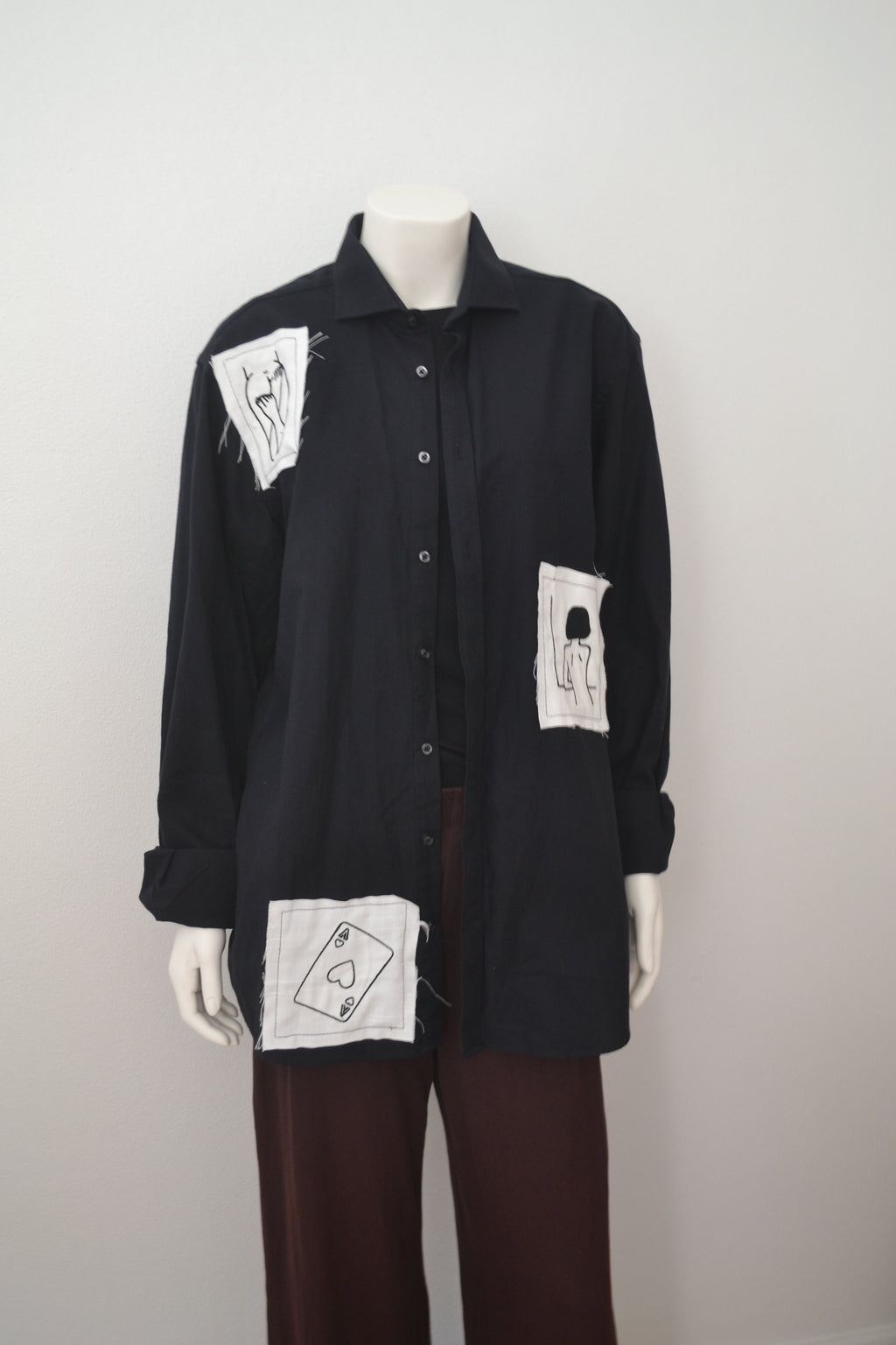 Sort skjorte forfra på mannequin med hvide patches