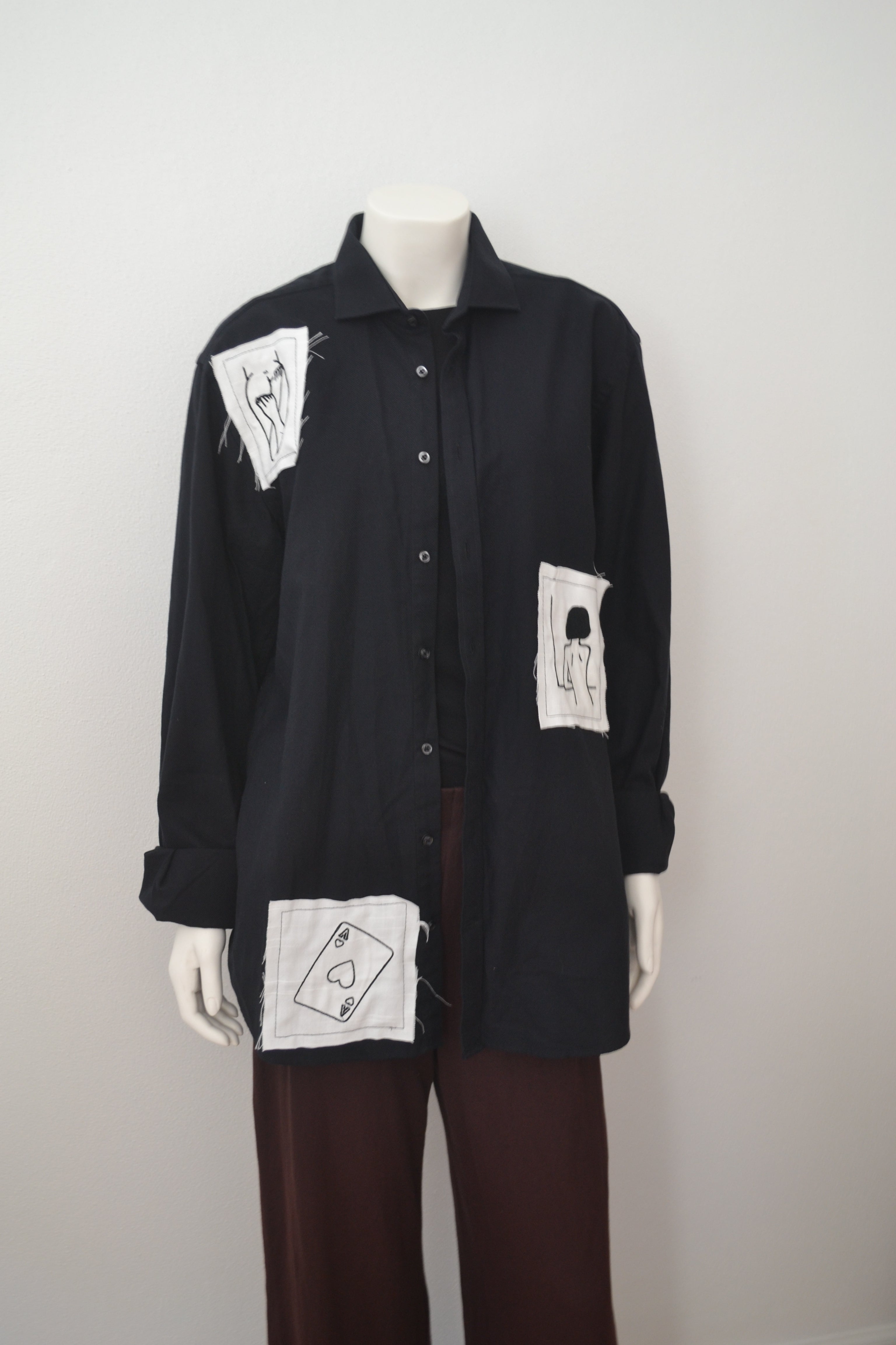 Sort skjorte forfra på mannequin med hvide patches