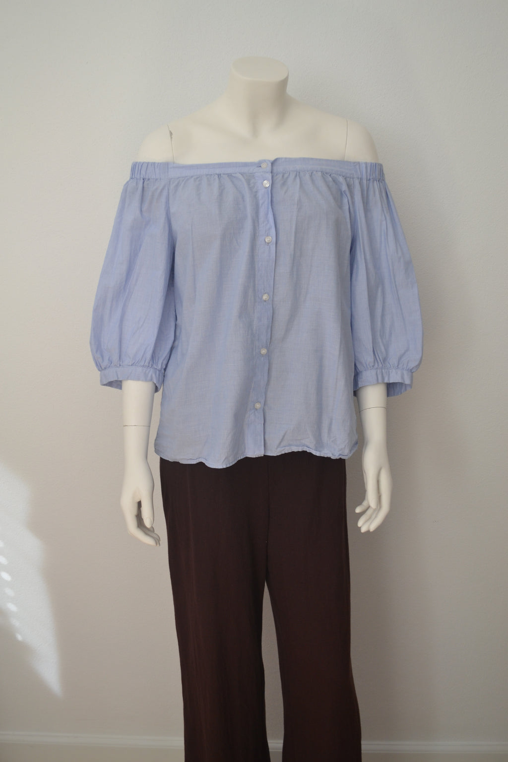Lys blå off-shoulder bluse forfra på mannequin