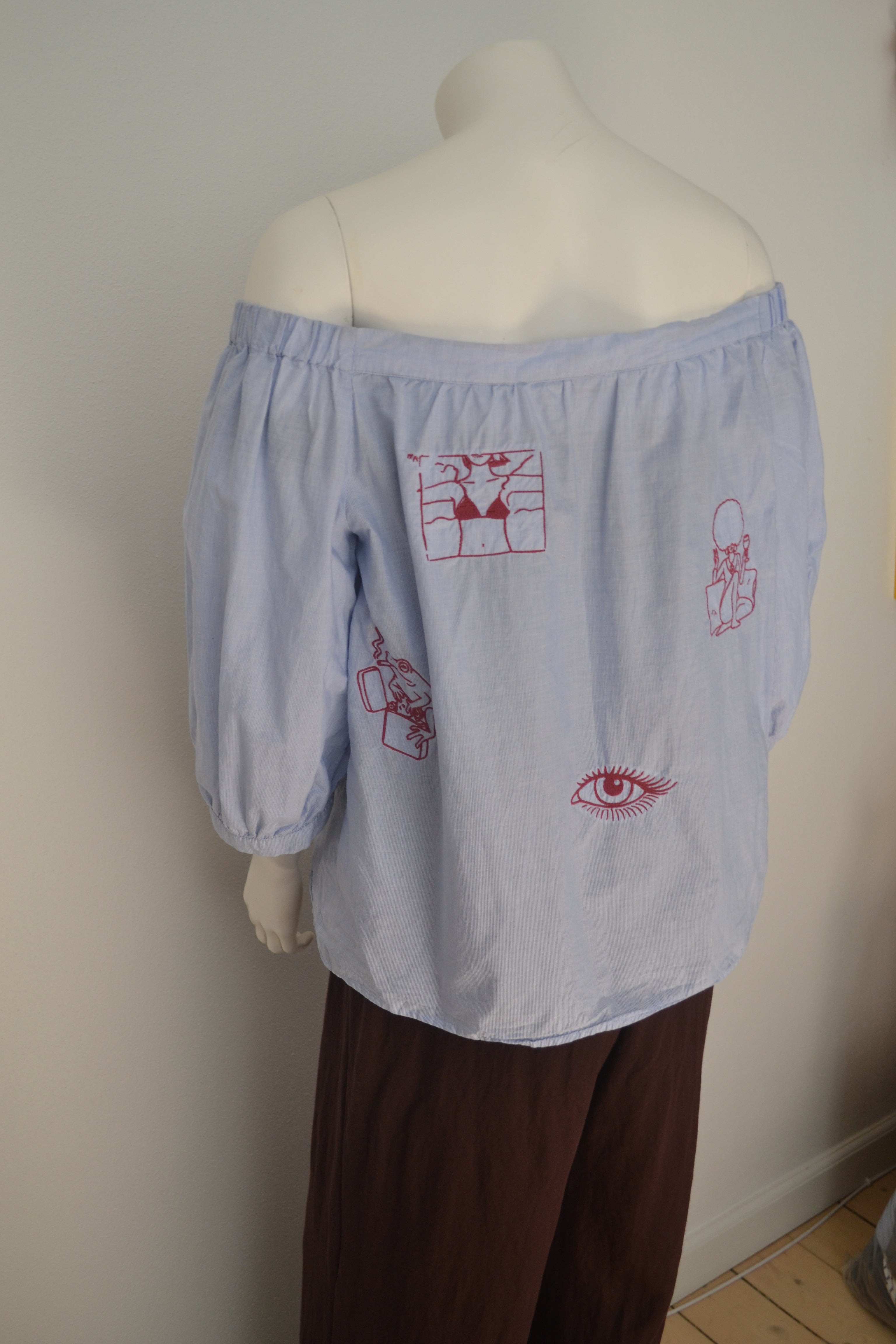Lys blå off-shoulder bluse bagfra fuld med bordeauxrøde broderede motiver