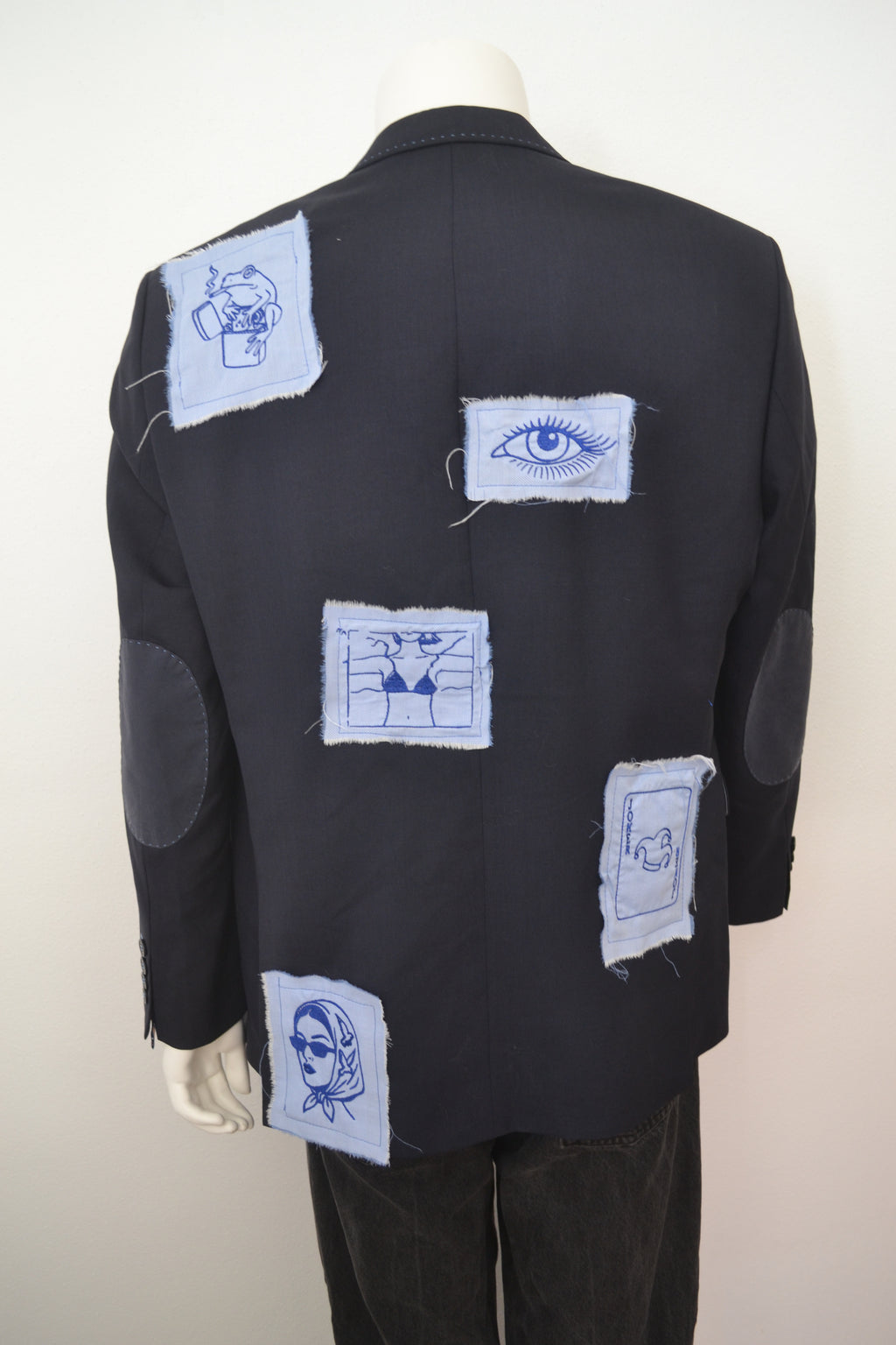 Sort blazer bagfra med broderede motiver på lyseblå patches