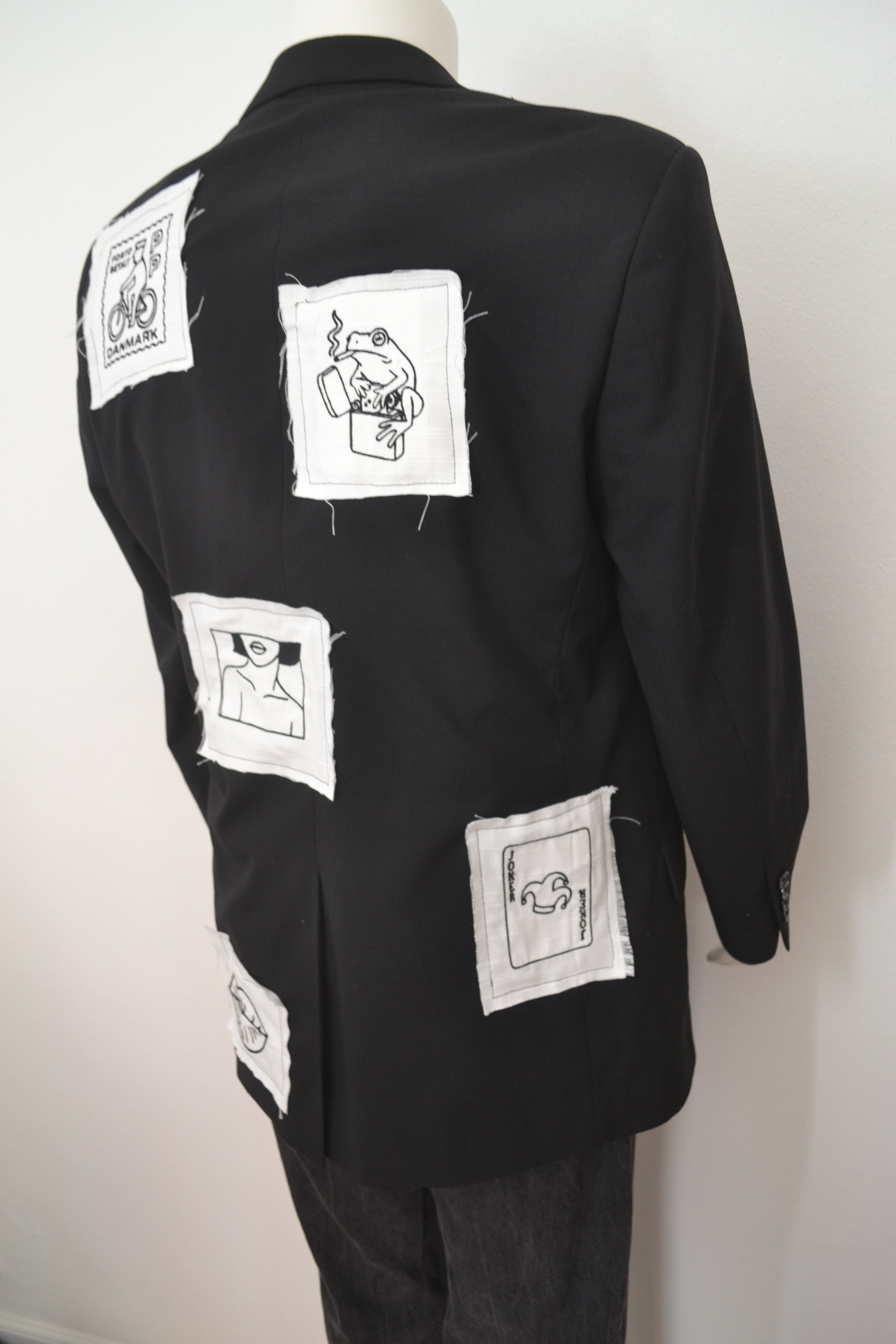Sort blazer bagfra med hvide patches og broderede motiver